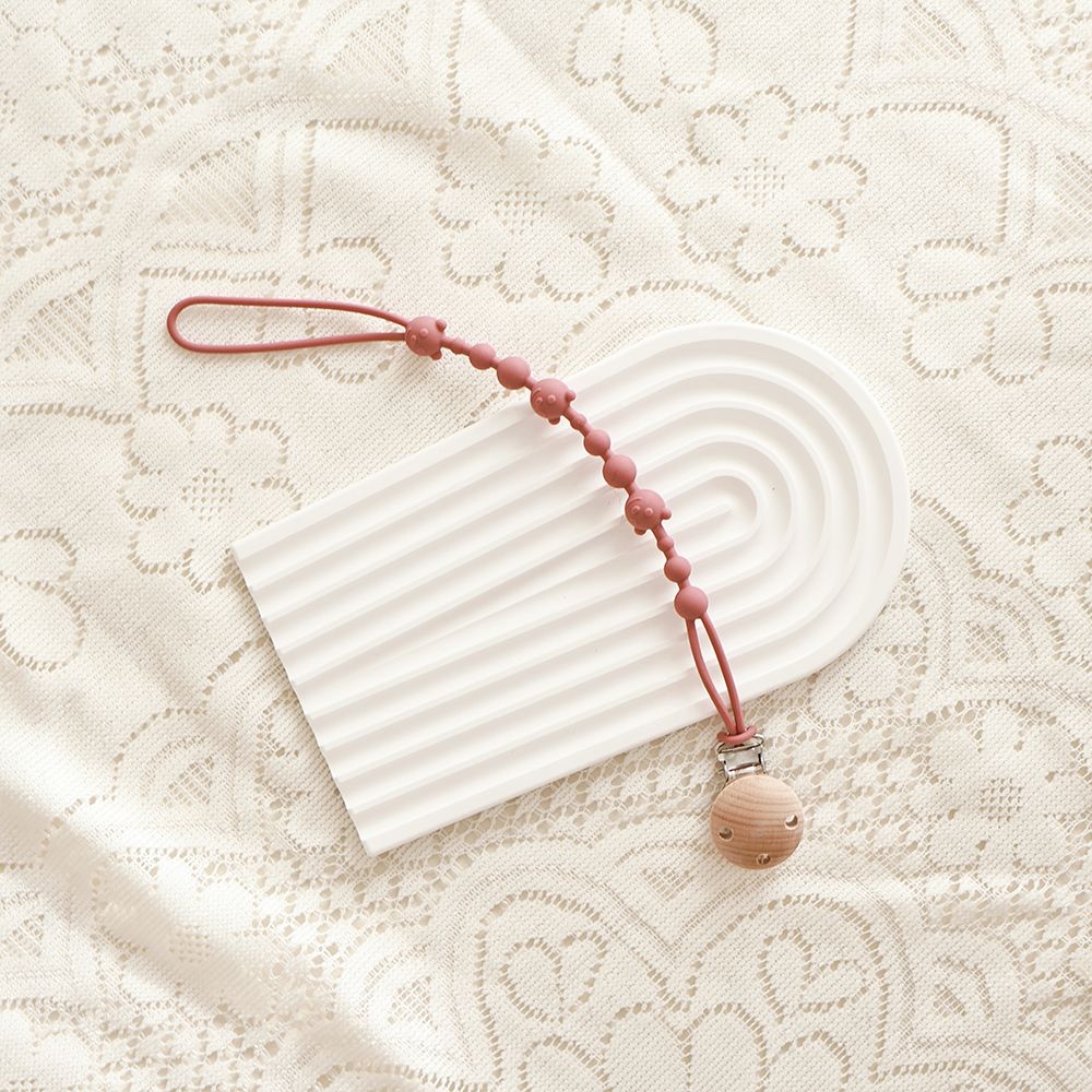 Silicone Dummy Clip, Beaded Soother Holder with Beech Wood Clip & Bear, Face Beads, 22 cm, 7 Colours, shown on a bed