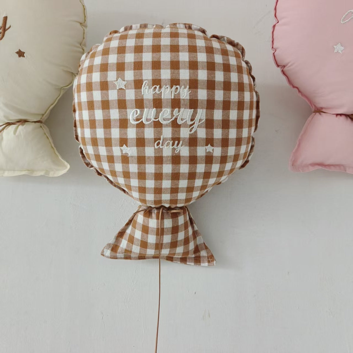 Balloon-shaped nursery cushion with an embroidered message on a nursery shelf – Brown Gingham, Happy Every Day