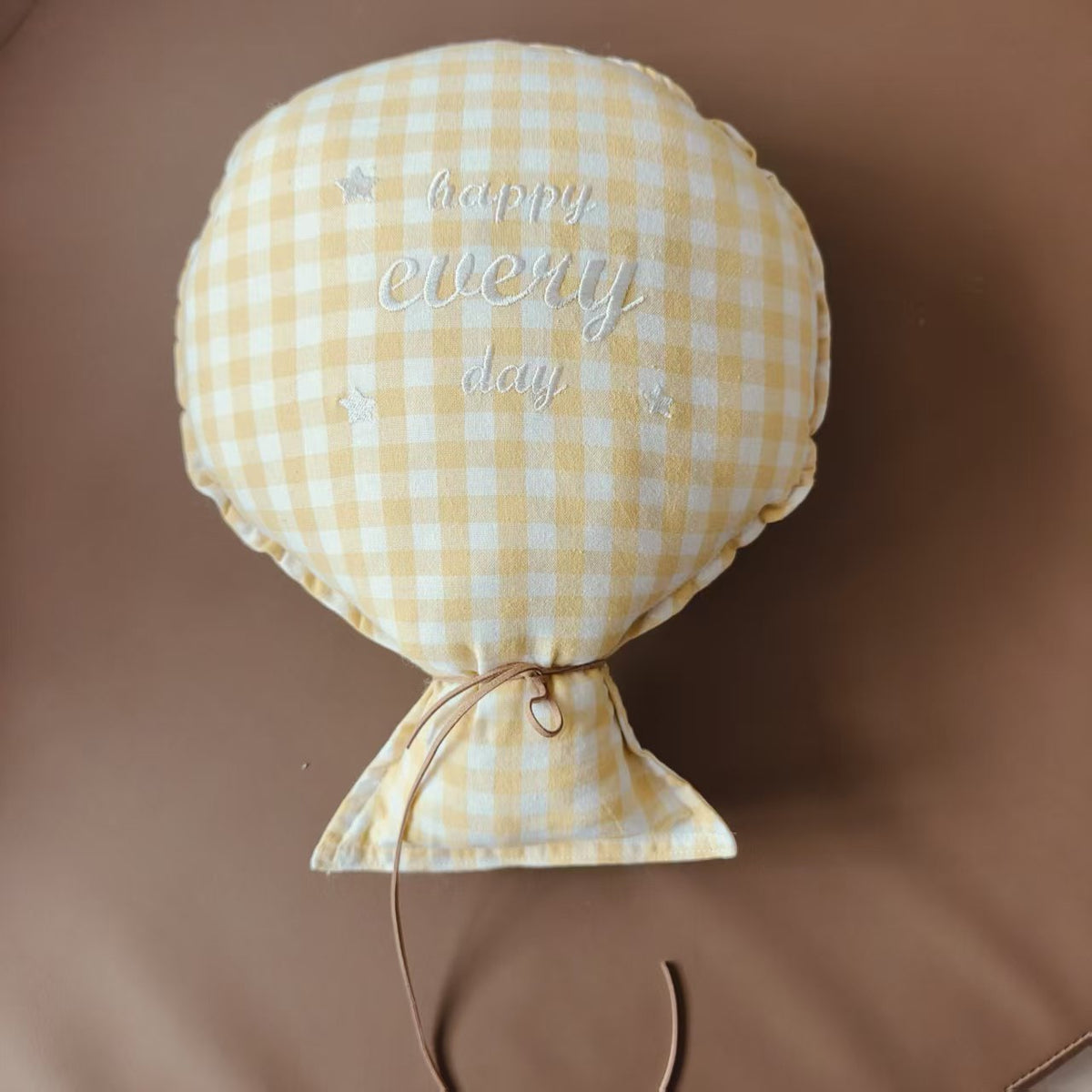 Balloon-shaped nursery cushion with an embroidered message on a nursery shelf – Yellow Gingham, Happy Every Day