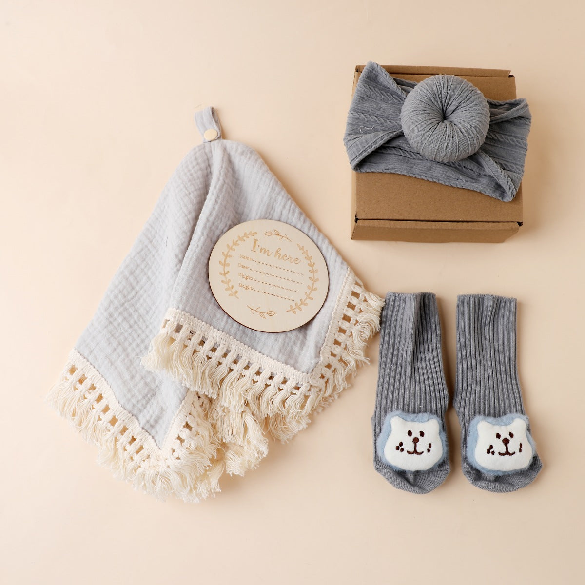 Grey boxed newborn gift set with tassel comforter, socks and brush