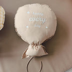 Balloon-shaped nursery cushion with an embroidered message on a nursery shelf – Mocha, Happy Every Day