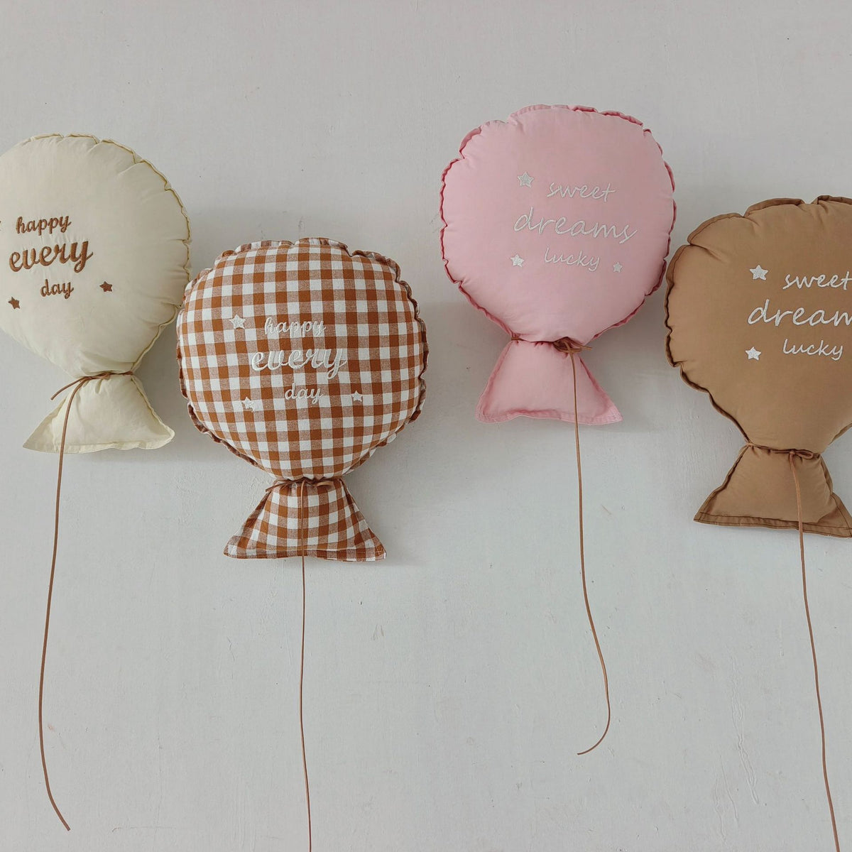 Balloon-shaped nursery cushion with an embroidered message on a nursery shelf