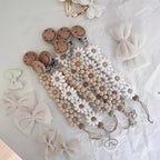 Silicone Daisy Dummy Clip, Beaded Soother Holder, shown on a bed