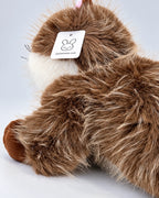 Realistic brown and white Ragdoll-style cat plush toy, lying down, back view