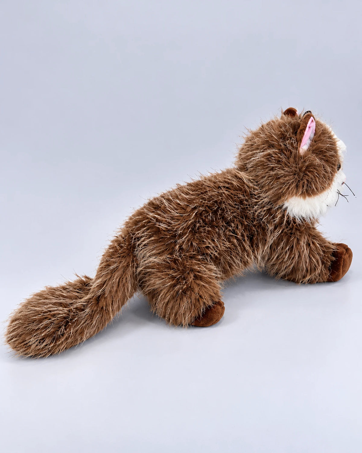 Realistic brown and white Ragdoll-style cat plush toy, lying down, back view