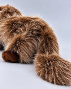 Realistic brown and white Ragdoll-style cat plush toy, lying down, close-up of the tail