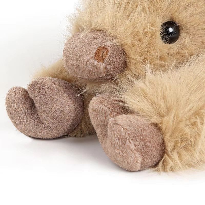 Lying Highland cow soft toy with shaggy golden-tan fur, fringe and brown hooves – view 3 of 7