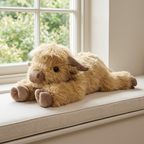 Lying Highland cow soft toy with shaggy golden-tan fur, fringe and brown hooves