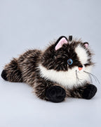 Realistic black cat plush toy, lying down, studio photo